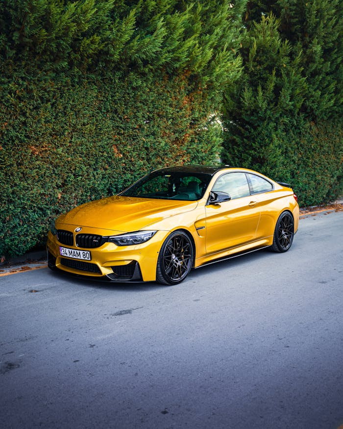 A sleek yellow sports car parked on a street in Ankara, surrounded by lush greenery.